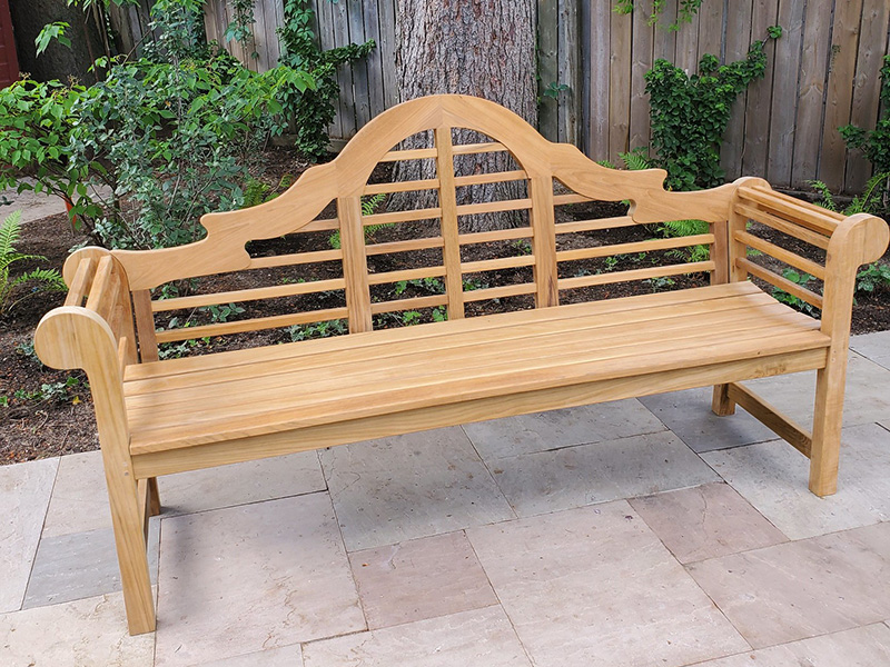 Light teak bench with arms and a slatted scrolled back