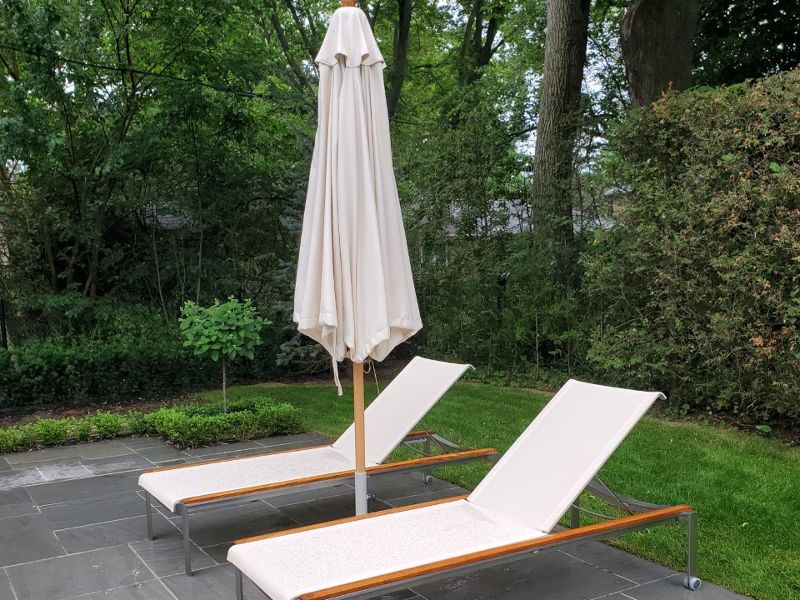Metal chaise lounges with white slings and a white umbrella